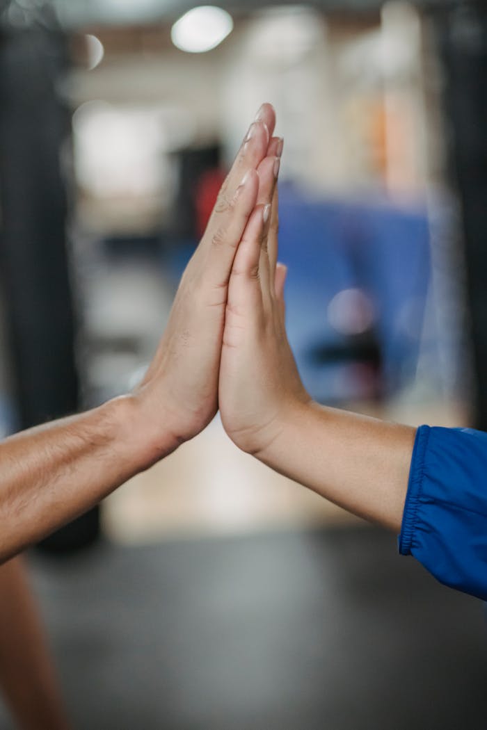 Crop faceless people clapping hands in room